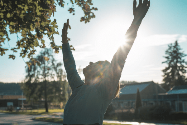 Person stretching outdoors at sunrise to restore energy on night shifts through light exposure and movement.